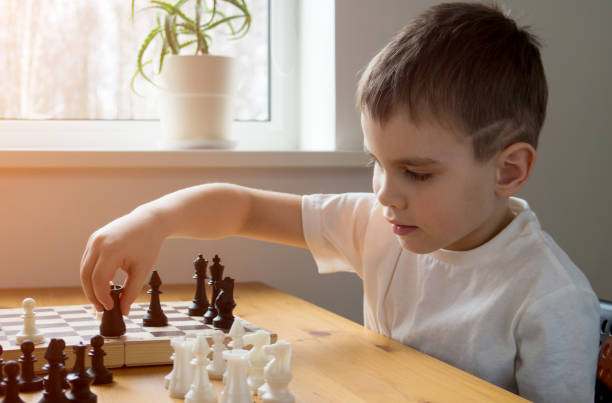 istock A preschool boy arranges pieces on a chessboard for playing chess. Board games. 1314859666