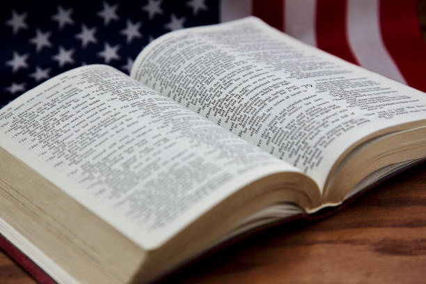 istock Open Bible with American flag behind on wood grain table 1314860823