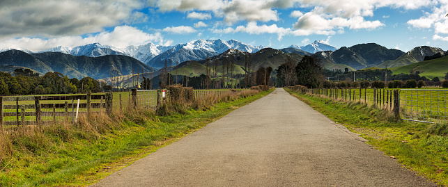 Rural country road heading through agricultural farming land  to the snow covered Tararua Ranges