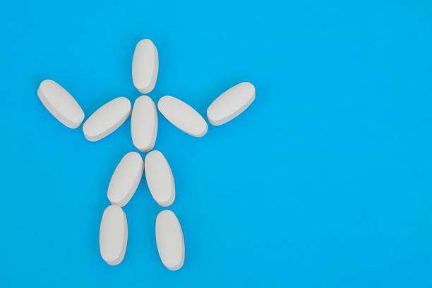 istock Human figure laid out from white oblong pills on blue background. Human skeleton. 1314864967