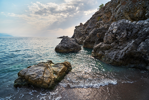 Rocky coast blue water Mediterranean Sea near Fethiye, Turkey, cloudy sky, back light