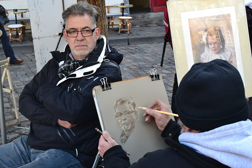 20.02.2012. Paris. France. Street arts of painting in painters hill in paris. An artist making a picture of mid mature of a man.