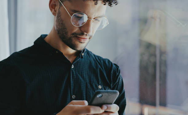 tiro de um jovem empresário usando um celular em um escritório - telephone dialing human hand office - fotografias e filmes do acervo