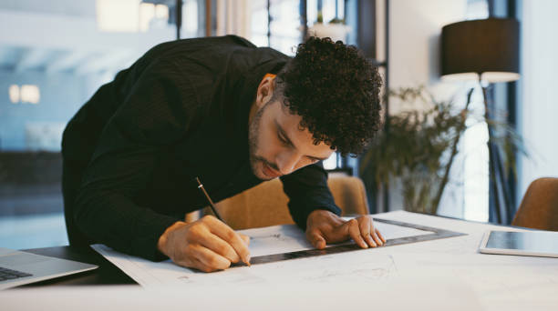 istock Shot of a young architect drawing building plans in an office 1314873818