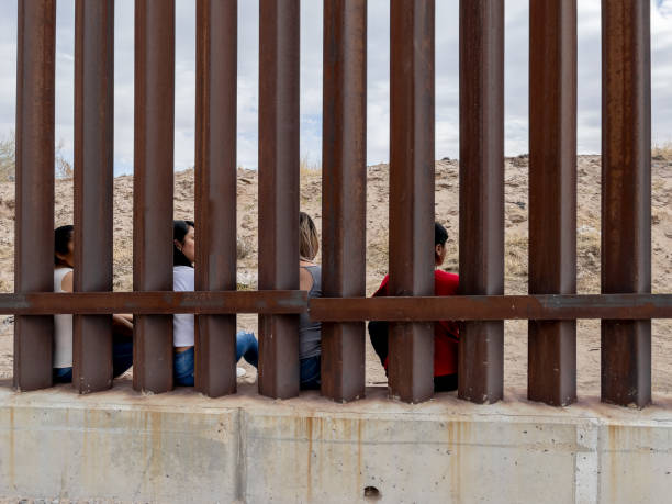 Group of Mexican People looking through the International Border Wall between Chihuahua Mexico and Texas, USA Group of Mexican People looking through the International Border Wall between Chihuahua Mexico and Texas, USA international border barrier stock pictures, royalty-free photos & images