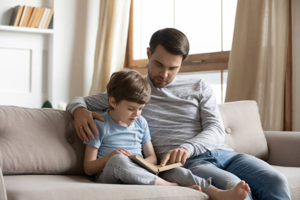istock Caring dad and small son reading book at home 1314877544