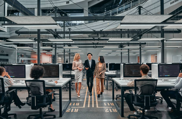 istock Three business people walk around a spacious large office with a lot of computers and talk about work. The concept of working with technology, online development and work. 1314878690