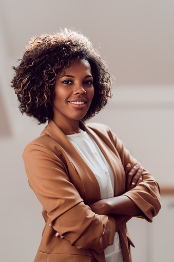 Portrait of young cheerful african american businesswoman wearing brown suit smiling and looking at camera