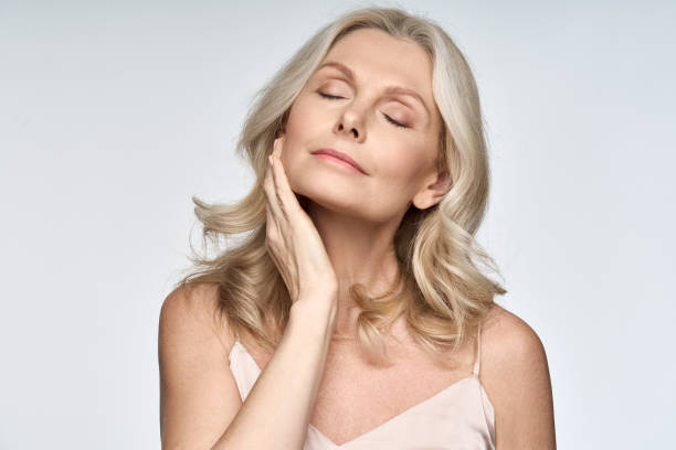 gorgeous senior older woman with closed eyes touching her perfect skin. beautiful portrait mid 50s aged woman advertising facial antiage lift products salon care tighten skin isolated on white. - adult beautiful caucasian equipment imagens e fotografias de stock