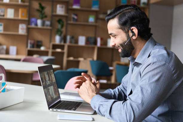 uomo d'affari sorridente indiano latino che indossa cuffie con riunione di gruppo virtuale chiamata di gruppo chattando con diverse persone nell'assistenza clienti. videoconferenza al computer con manager e dipendenti. - internet computer hands free device telephone foto e immagini stock