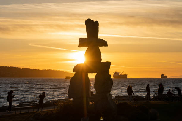 scultura in pietra di inukshuk all'ora del tramonto a english bay beach, vancouver city, canada. - indigenous culture immagine foto e immagini stock