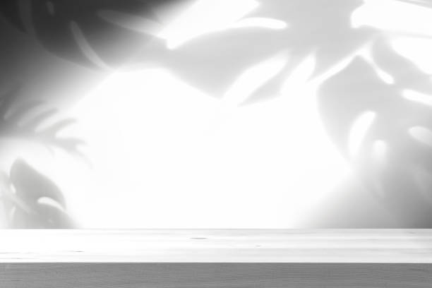 istock Empty wooden table with shadow of tropical leaves on background with copy space 1314904541