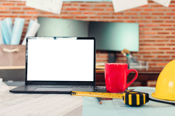 istock Laptop, cup of coffee, design plan and safty helmet on the table. 1314905643