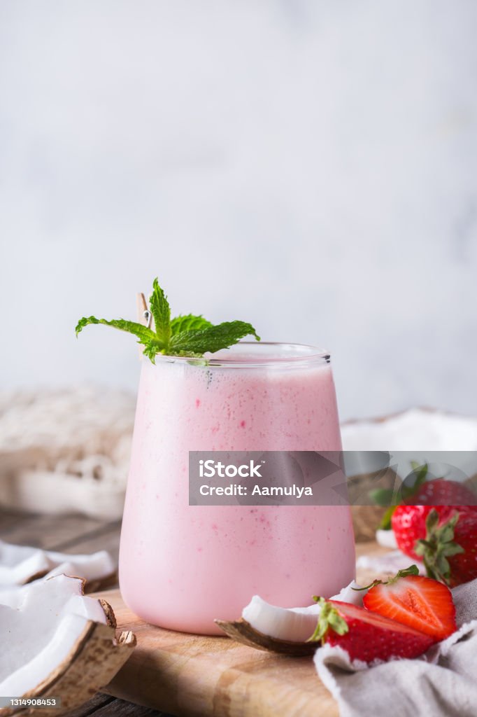 Healthy vegan coconut and strawberry indian lassi Healthy organic coconut and strawberry lassi, smoothie, shake, indian drink beverage with yogurt and fresh local fruits. Vegan concept to reduce food carbon footprint Strawberry Stock Photo