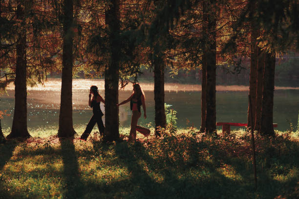 coppia di donne hippie camminano mano nella mano nella foresta - pacifism foto e immagini stock