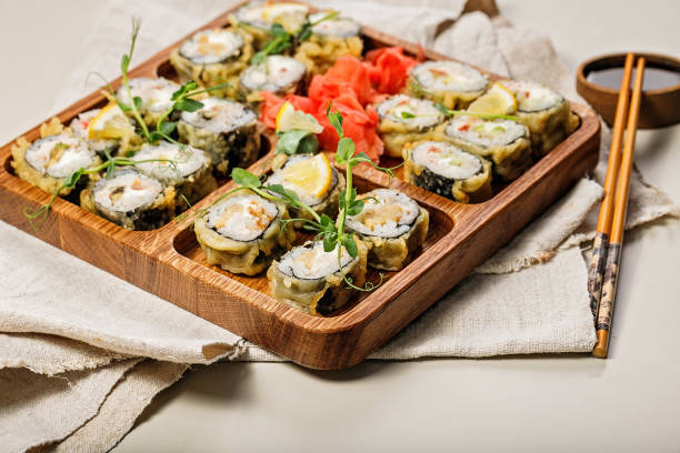 istock Hot rolls with eel, Japanese omelette, cream cheese, fried onions and unagi sauce, decorated with fresh herbs. Japanese food on a bamboo platter, bamboo sticks, sauce on a light background. Copy space 1314913807