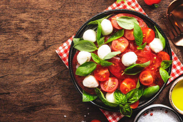 레드 토마토와 모짜렐라 치즈를 곁들인 여름 이탈리아 샐러드 카프리세와 그린 바질 잎, 올리브 오일 드레싱. 상단 보기, 나무 테이블 - caprese salad heirloom tomato salad food 뉴스 사진 이미지