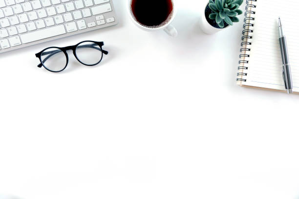 istock Modern white office desk table with keyboard computer, notebook, tree, glasses and cup of coffee. Top view with copy space, 1314916602