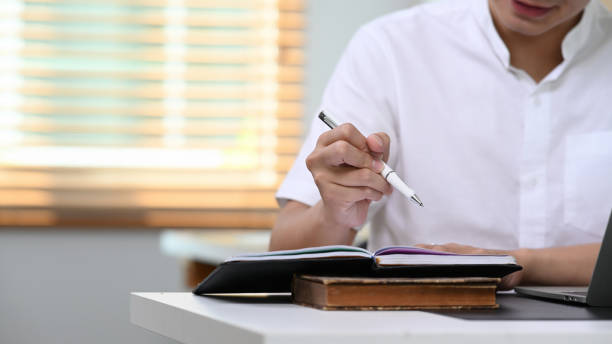 istock Cropped shot businessman writing notebook with pen on table at home office. 1314916736