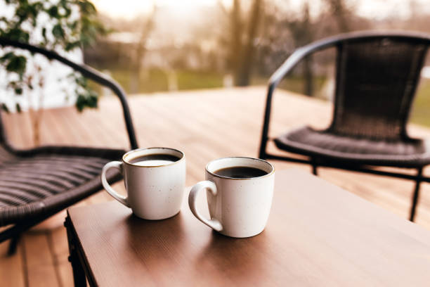 dos tazas de café sobre la mesa en la terraza marrón de madera durante la puesta del sol de la noche - bancal fotografías e imágenes de stock