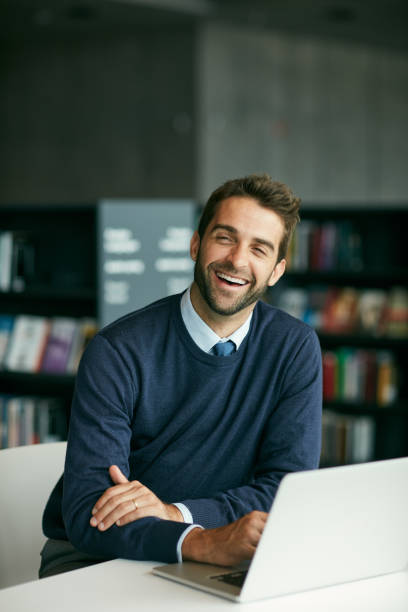 istock Cropped shot of a handsome young man sitting in a library alone and laughing while using a laptop 1314920951