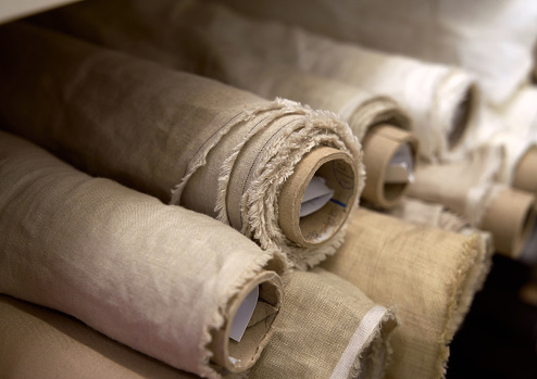 Close-up set of linen textile rolls. Online sale or tailoring objects concept. Fabrics retail store, atelier, drapery or textile shop. High quality image
