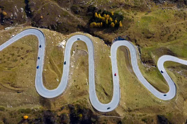 Winding mountain road with car traffic, Julier Pass, Graubunden Canton, Swiss Alps, aerial drone view.