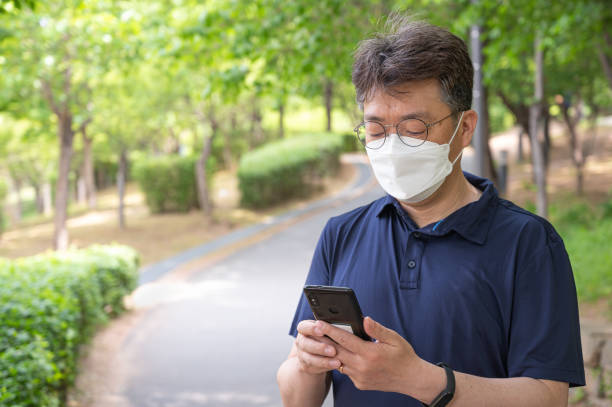 istock Middle-aged Asian man walking alone in a forest path wearing a face mask. 1314923396