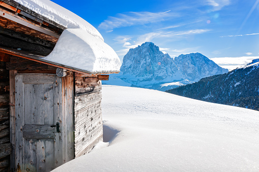 Old wooden shelter in Dolomites mountain. In the background Sassolungo peak.