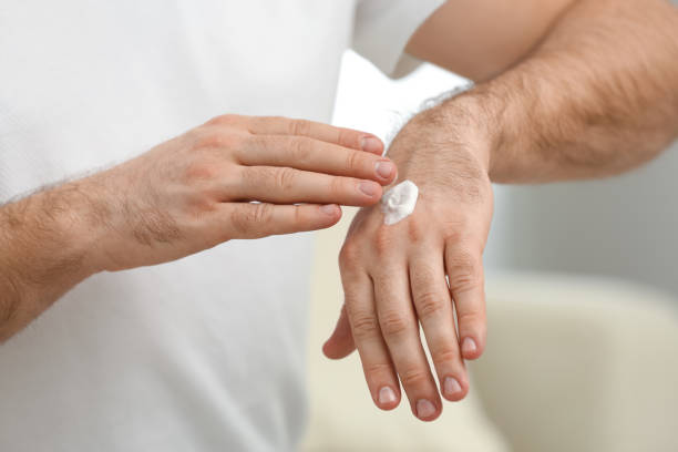 istock Man applying cream onto hand on blurred background, closeup 1314929611