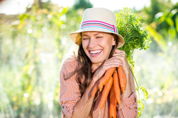 красивая фермерская женщина с морковью - mature women portrait hat human face стоковые фото и изображения