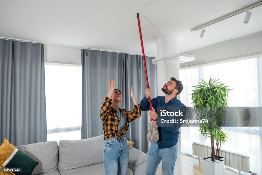A young couple stares at the ceiling and yells because a neighbor upstairs is having a party with loud music or renovating an apartment and workers are drilling with heavy tools Neighbor Stock Photo
