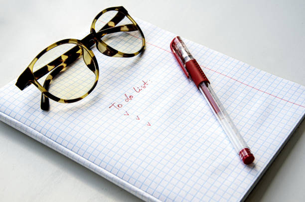 istock Horn-rimmed glasses, red ink pen on a checkered notebook. 1314937616