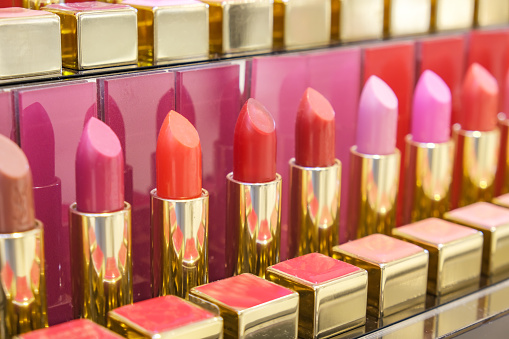 Cosmetic counter with lipstick in vibrant reds. Fashion and beauty industry, decorative cosmetics. Selective focus, blurred background