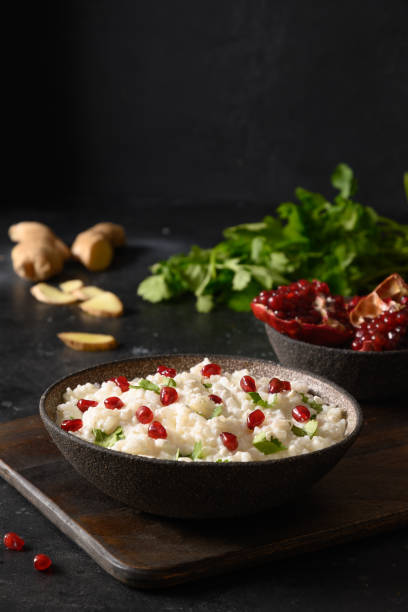 Curd Rice with pomegranate, cilantro, mustard seeds, ginger on a black background. Indian cuisine