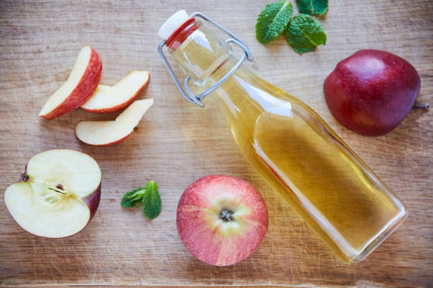 boven het hoofd ontsproten van een fles azijn van de appelciderazijn op een houten lijst - vinegar stockfoto's en -beelden