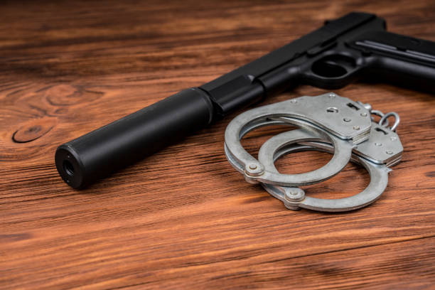 istock A pistol with a silencer and handcuffs on the table. 1314944279