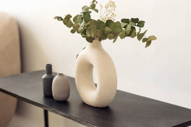 istock White creative stylish vase with eucalyptus branches and gypsophila on a black shelf.Interior design.Minimalistic style 1314945438