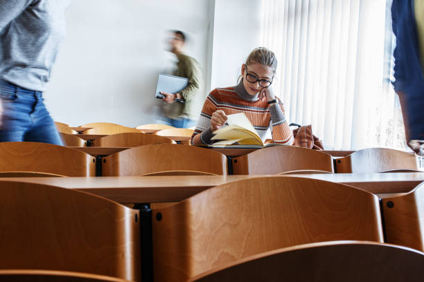 Young blond hair female student taking a test in university classroom. stock photo