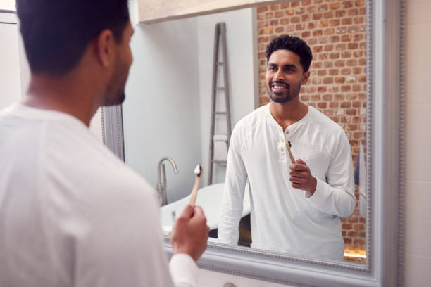 istock Man Wearing Pyjamas At Home In Modern Bathroom Brushing Teeth In Mirror 1314946699
