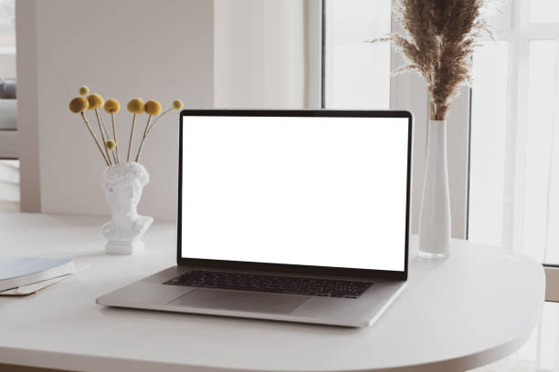 istock Laptop with blank white screen in office desk interior. Stylish workplace mockup. 1314948192