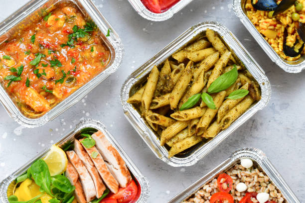 Different aluminium lunch box with healthy natural food pasta pesto, spelt, paella, quinoa, chicken salad, curry. Food delivery. airlines food. airline meals and snacks . takeaway food airplane food stock pictures, royalty-free photos & images