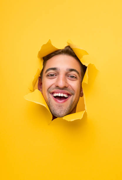 istock Happy guy looking at camera through hole in paper 1314949362