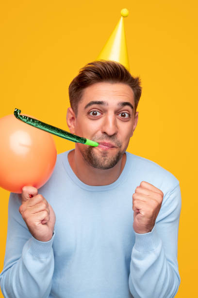 istock Cheerful guy with party balloon blowing noisemaker 1314949390