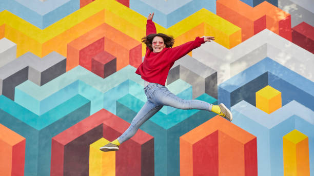 istock Excited female jumping against graffiti wall 1314949462