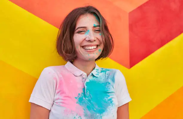 Photo of Happy young female laughing near colorful wall