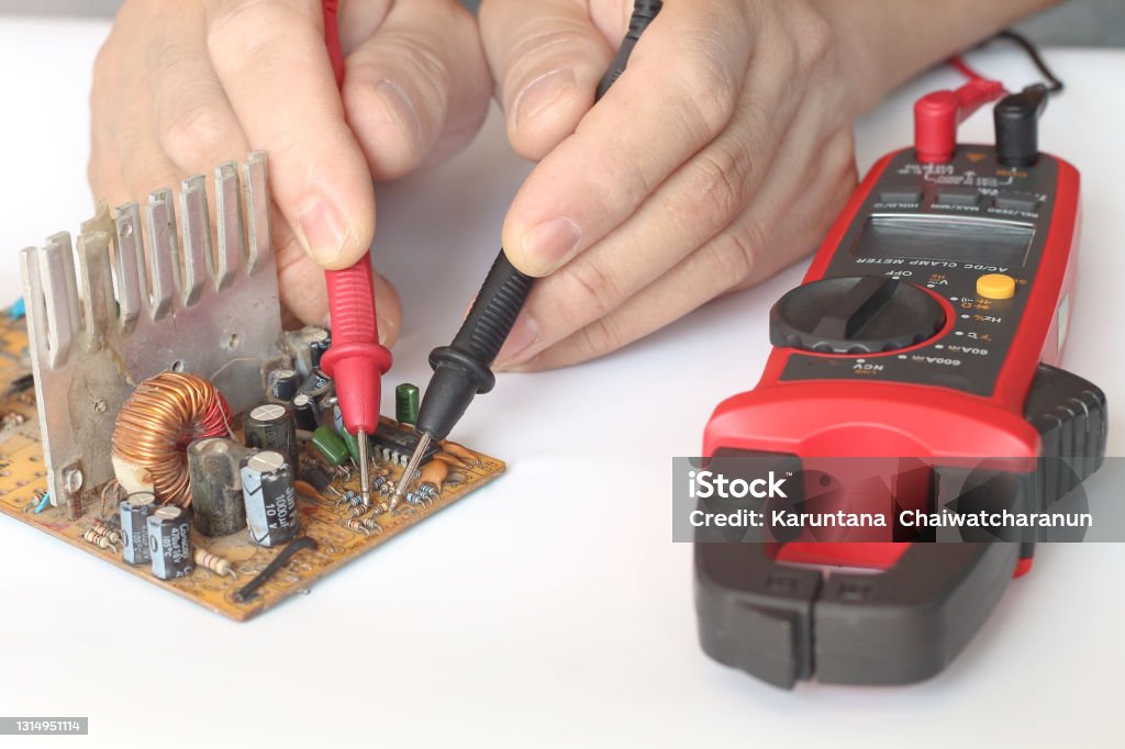 Close up of male hands repairing of electronic, circuit board with multimeter tester. Adult Stock Photo