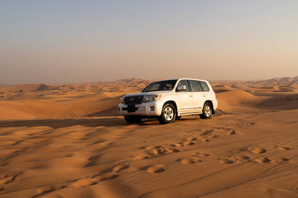 excursion safari dans le désert aux émirats arabes unis. voiture de safari de désert de quatre roues motrices conduisant dans le sable de désert sur le coucher du soleil - 4x4 desert sports utility vehicle dubai photos et images de collection
