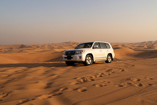 Desert safari tour in UAE. Four wheel drive desert safari car driving in desert sands on sunset