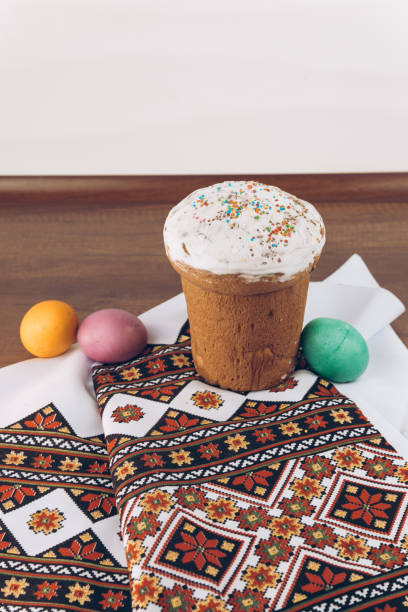 istock Ukrainian embroidered shirt and Easter cake on a wooden table and Easter eggs of different colors - yellow eggs, green and purple eggs. Easter eggs and Easter cake on an embroidered towel. 1314953624
